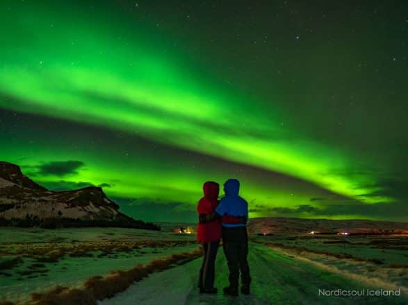 2 personnes sous les aurores boréales, également appelées lumières du nord, en Islande