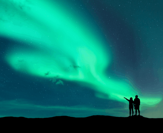 Silhouette of two people looking at the northern lights.