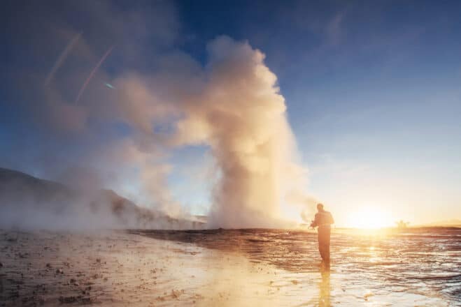 Eruption of Strokkur geyser in Iceland. Winter cold colors, sun lighting through the steam.