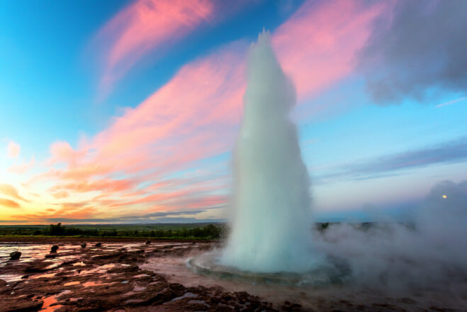 The hot spring Strokkur erupting in front of a pink sky