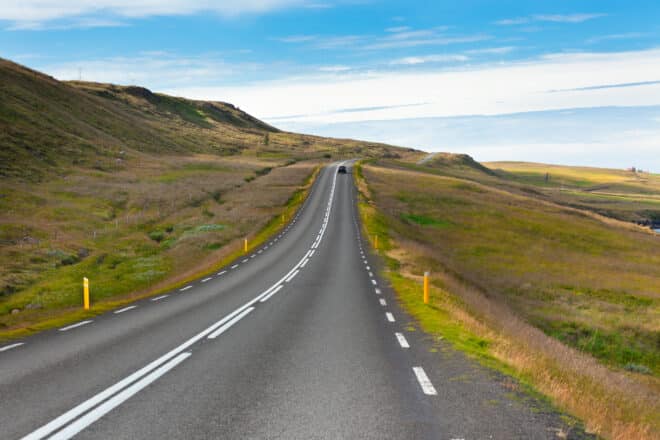 Carretera a través del paisaje islandés bajo un cielo azul de verano.