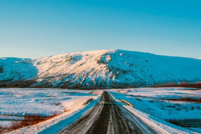 Típica carretera islandesa cubierta de nieve con palitos amarillos a un lado