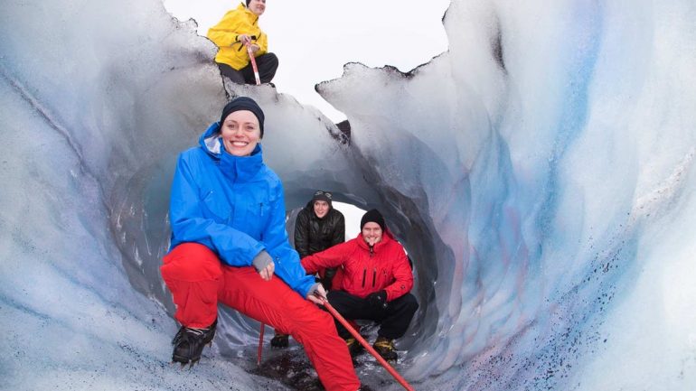 Excursionistas del glaciar explorando una grieta en el sur de Islandia