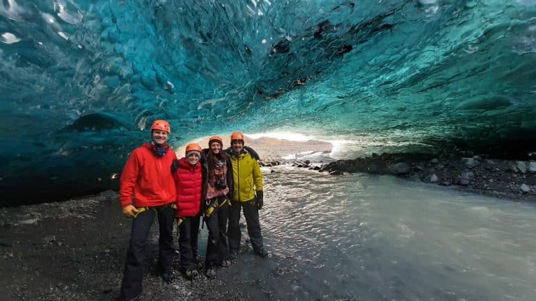 Un groupe de personnes debout devant les murs bleus d'une grotte de glace en Islande