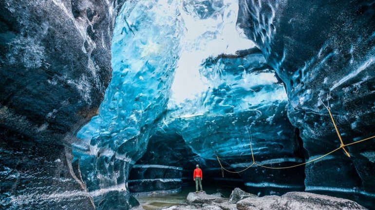 Un hombre parado dentro de una cueva de hielo en Islandia.