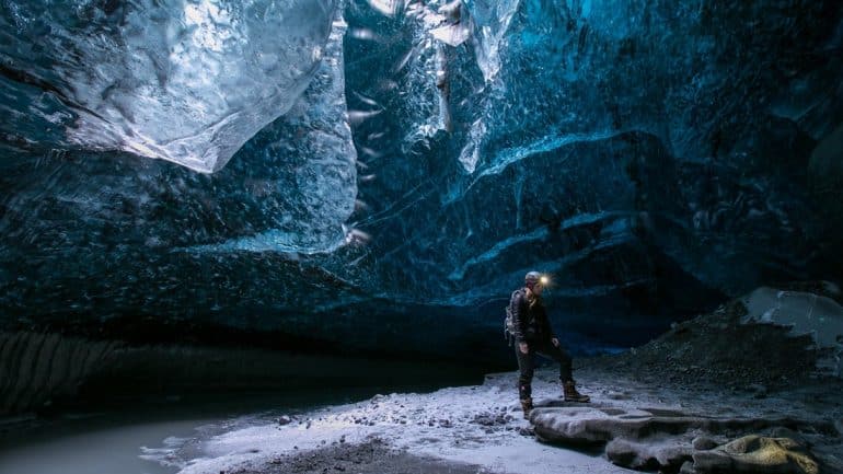 Un homme debout à l'intérieur d'une grotte de glace dans le parc national de Vatnajökull, Islande