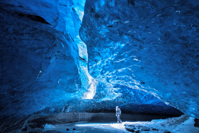 Una mujer de pie en una cueva de hielo azul en Islandia