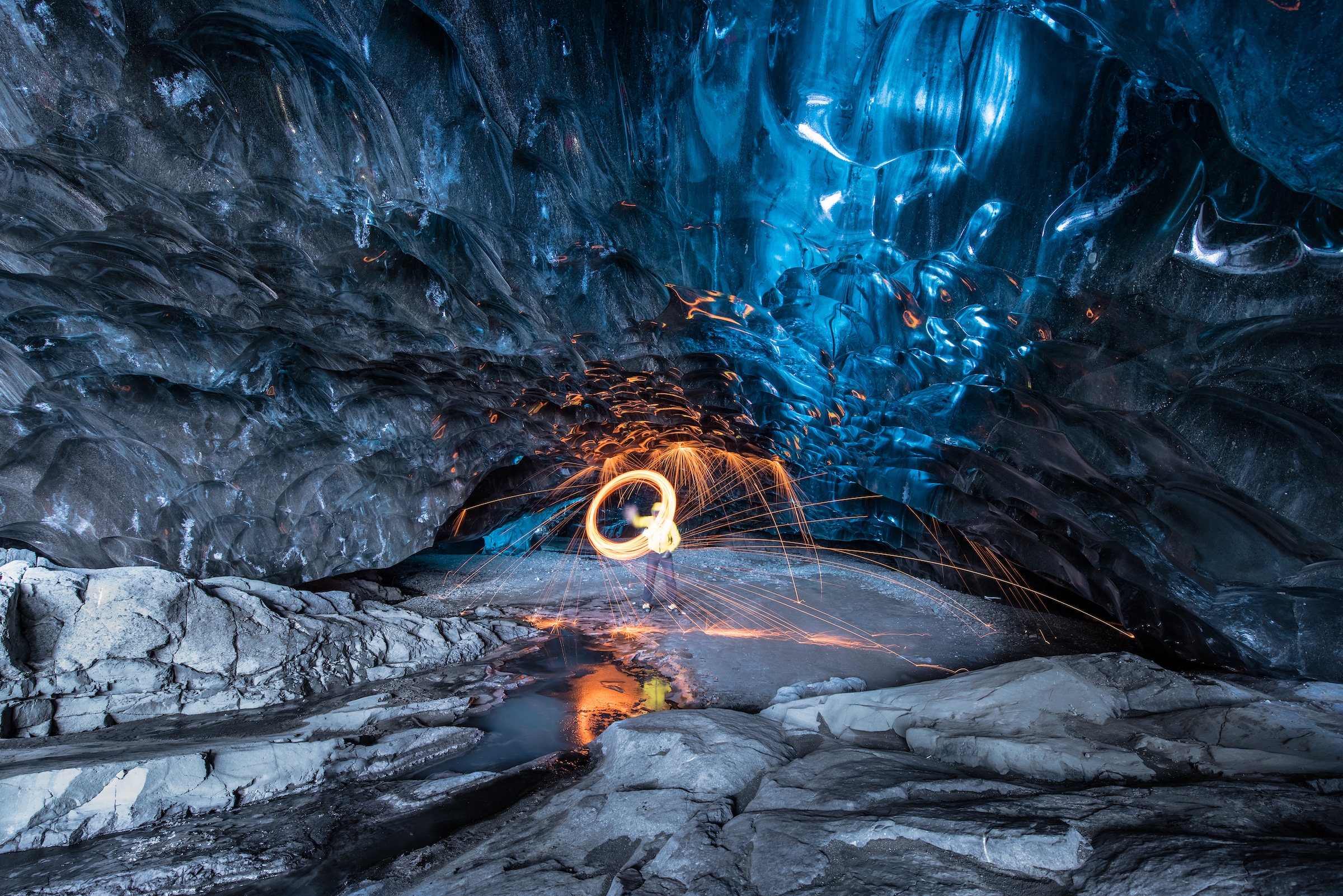 A man swinging a light inside an ice cave in southeast Iceland