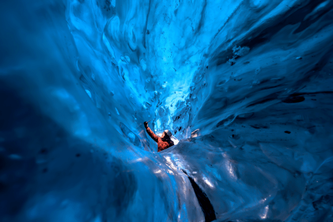 A man surrounded by blue ice inside and ice cave in Iceland