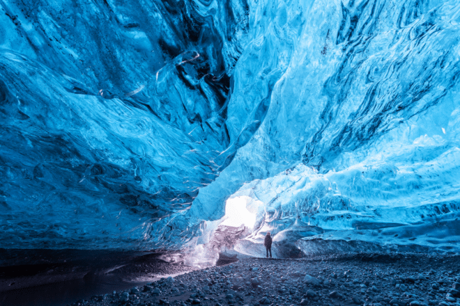 A man standing inside a blue ice cave in Iceland