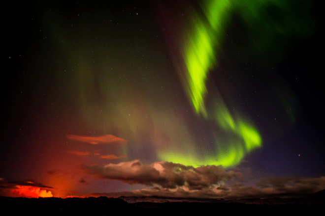Aurora boreal sobre una erupción volcánica en Islandia.