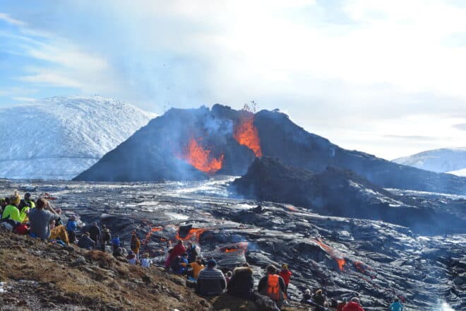 Un grupo de personas viendo una erupción volcánica en Islandia.