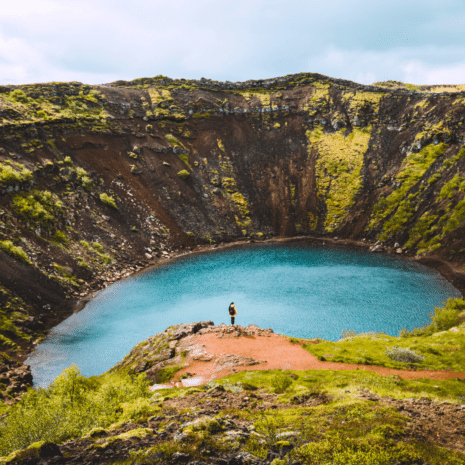 Una mujer de pie en el borde del cráter Kerid cerca del Círculo Dorado, Islandia.