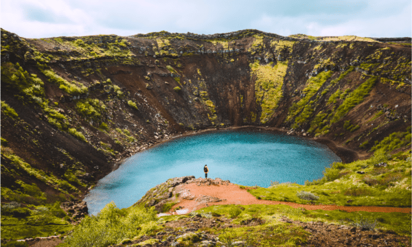 A woman standing on the rim of Kerid Crater near the Golden Circle, Iceland.