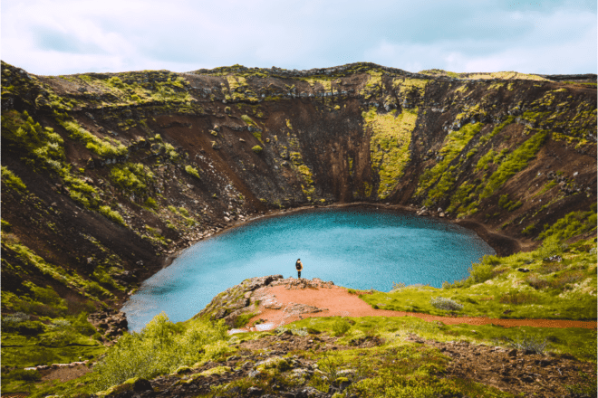 A woman standing on the rim of Kerid Crater near the Golden Circle, Iceland.
