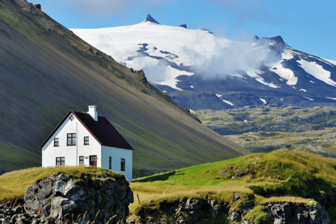 Una pequeña casa en el pueblo de Arnarstapi en la península de Snæfellsnes, con montañas al fondo.