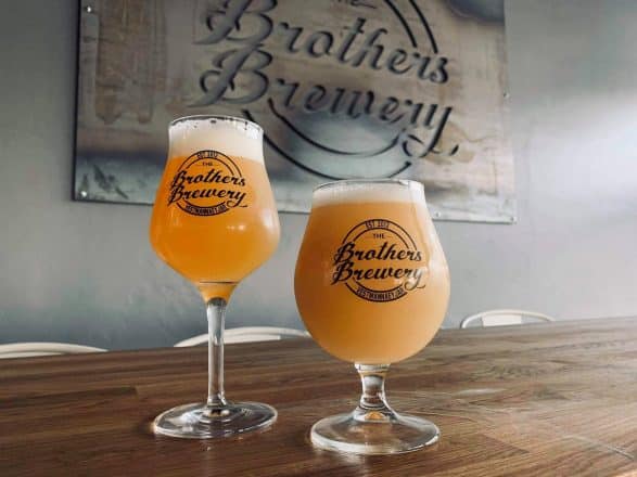 Two glasses of beer in front of a sign saying Brothers Brewery