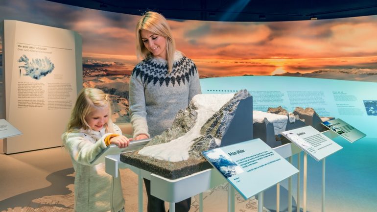 A mother and child exploring a model of a glacier at Perlan Museum in Reykjavik, Iceland
