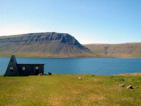 Verlaten huis bij een fjord en een berg in de Westfjorden van IJsland.