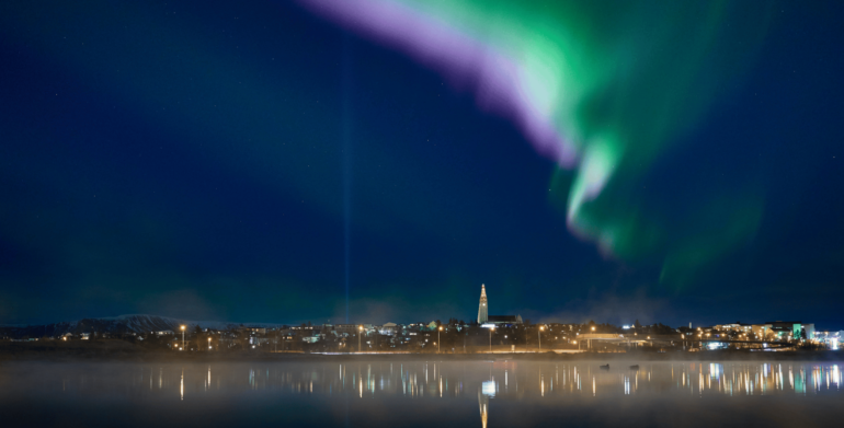 Green and purple Northern Lights above Reykjavik City