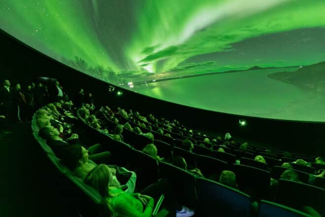 Gente en un planetario en Islandia viendo la aurora boreal.