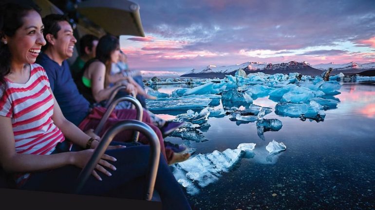 Personas suspendidas en un simulador de vuelo virtual mirando una laguna glaciar en Islandia.