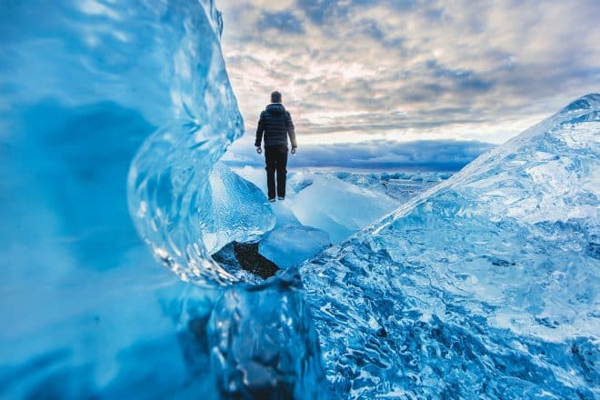 Un hombre parado frente al hielo en la laguna glaciar Jökulsárlón