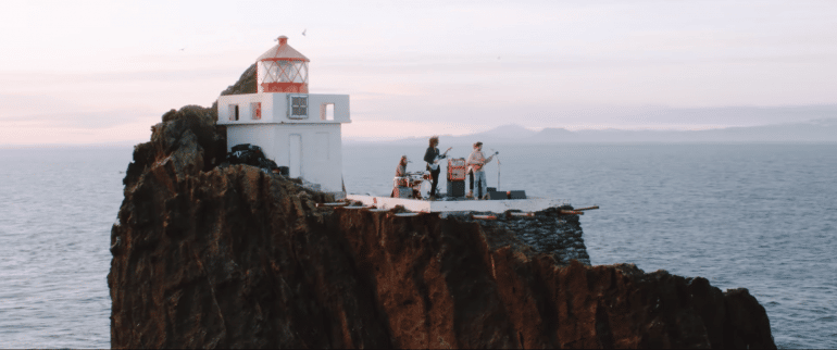 The Icelandic band Kaleo in front of the lighthouse at Thridrangar Cliffs.