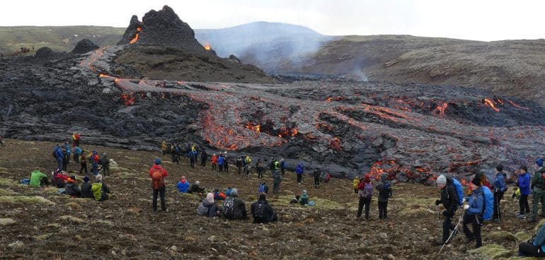 Tourists in front of an erupting volcano in Iceland.