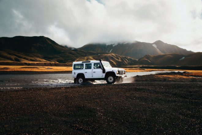 A white car crossing a river in the Icelandic Highlands.