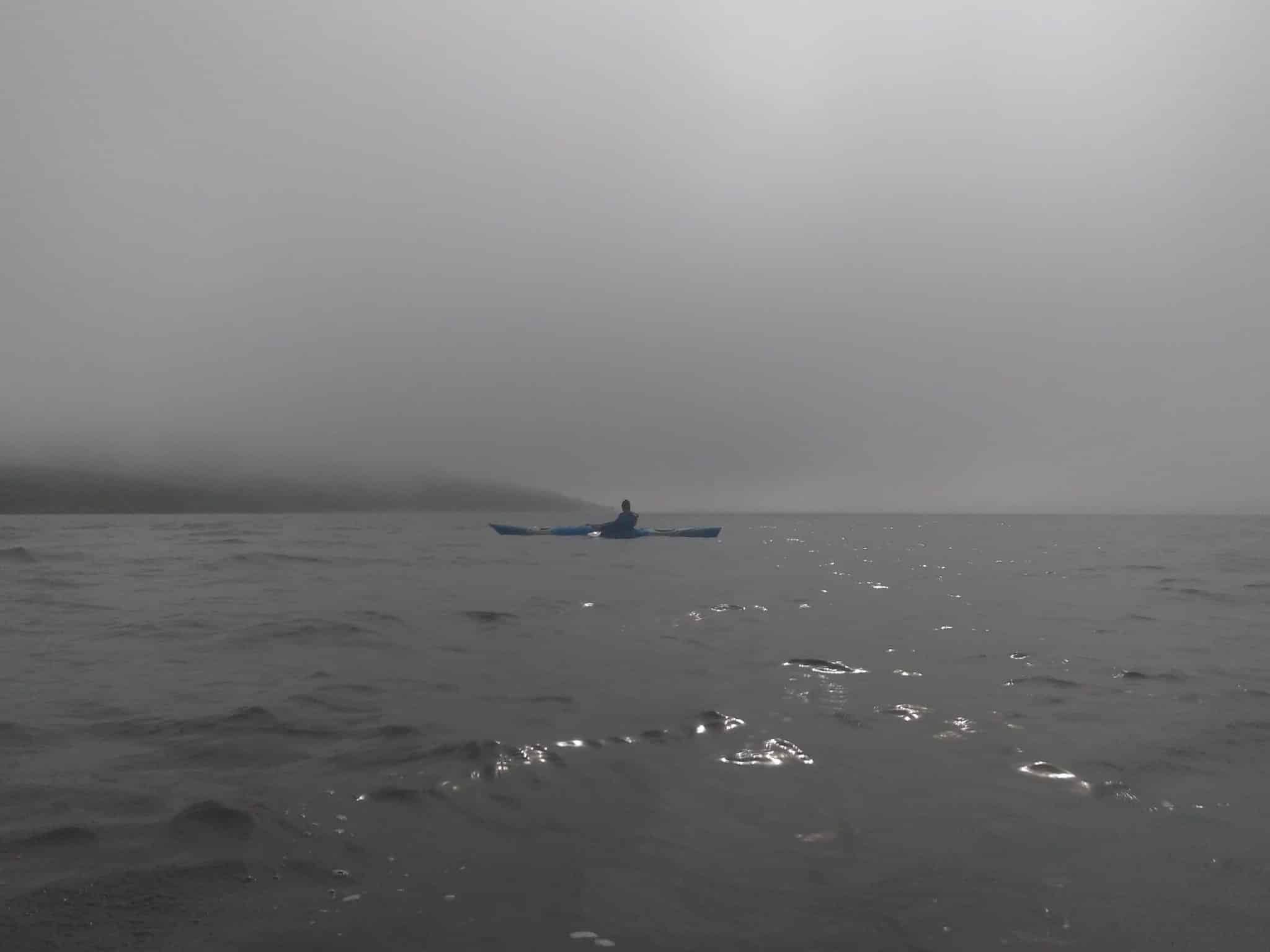A lone kayaker surrounded by fog in North Iceland.