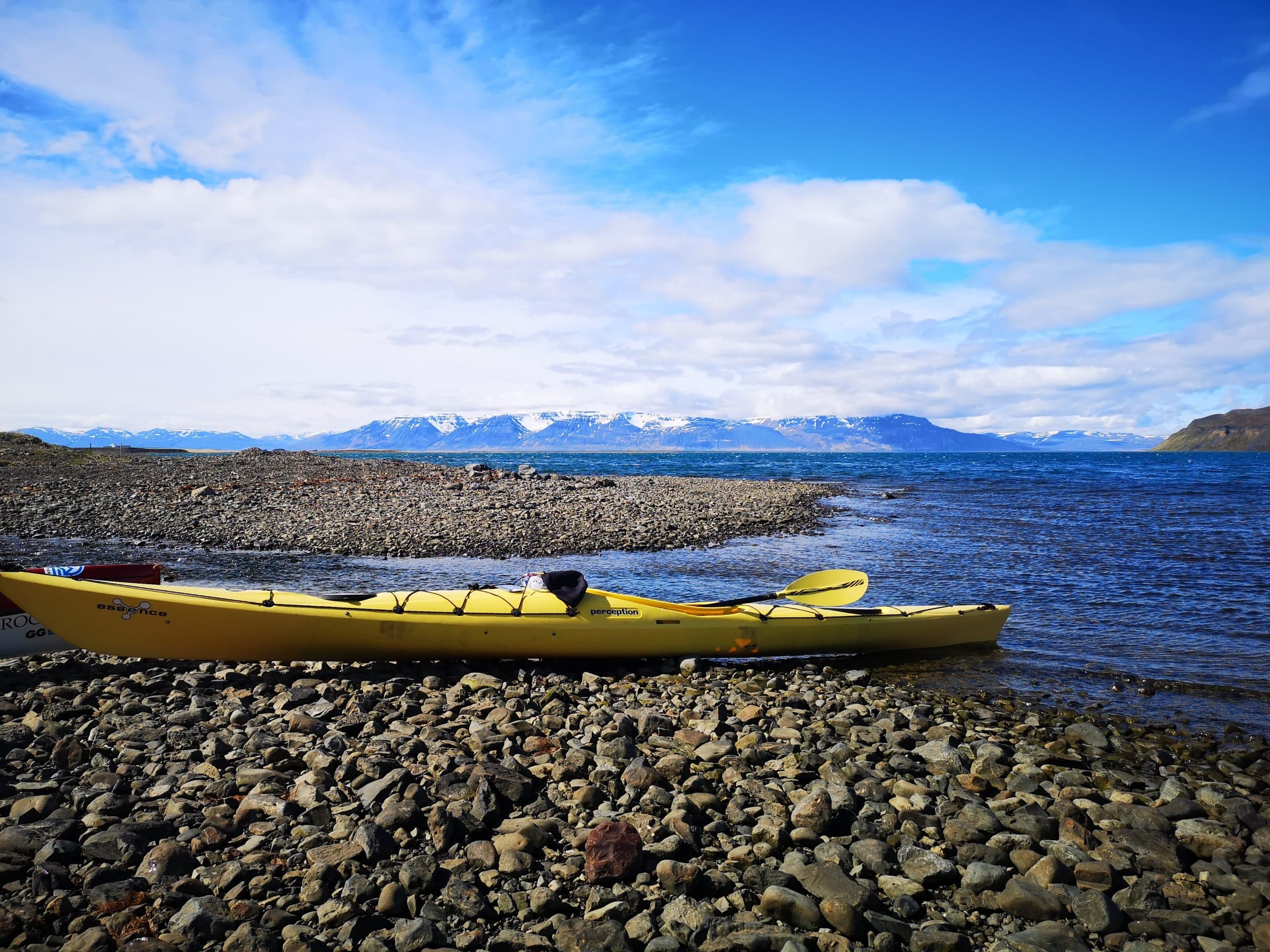 A view of a kayak on a beach, North Iceland's mountains in the background.