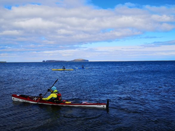 Tres kayakistas en el océano azul en el norte de Islandia.