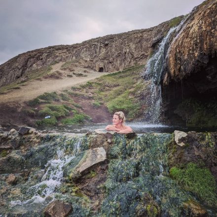 Una mujer bañándose en una cascada de aguas termales en el este de Islandia