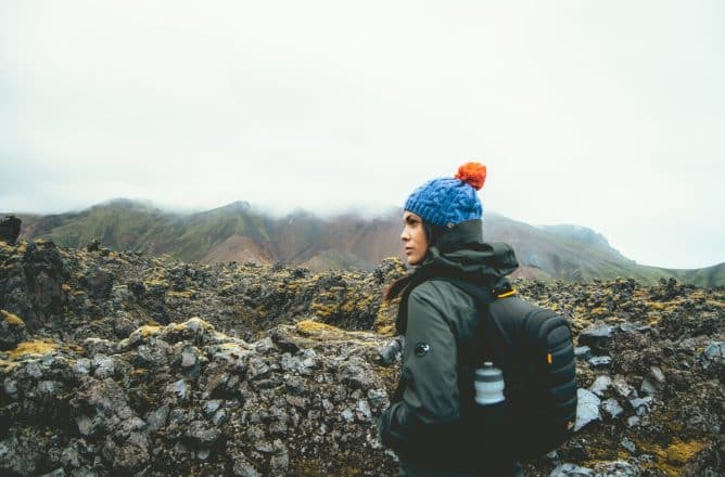 Une femme en vêtements de plein air près d'un champ de lave en Islande