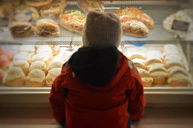 Un niño parado frente a pasteles en un escaparate.