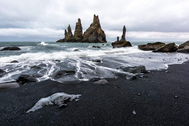 Formations rocheuses de basalte sur une plage de sable noir dans le sud de l'Islande.