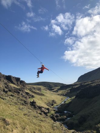 Een persoon op een zipline over een canyon in Zuid-IJsland