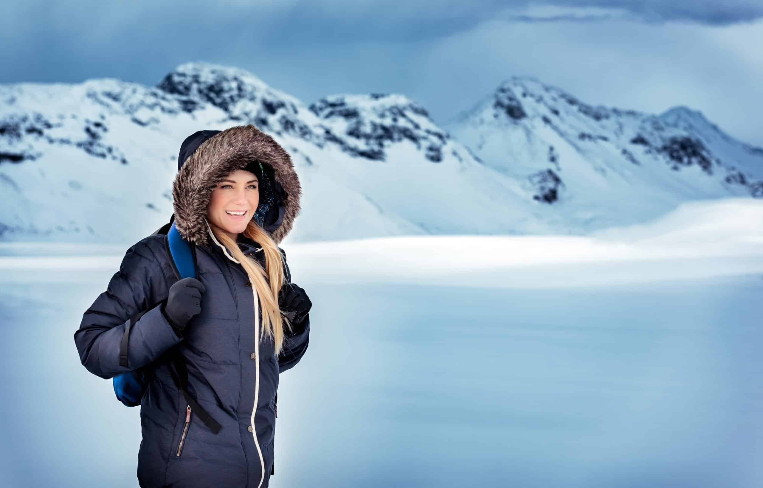 Mujer feliz con mochila viajando por las montañas nevadas de Islandia