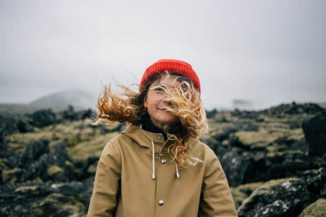 Femme devant un champ de lave en Islande avec le vent soufflant ses cheveux.
