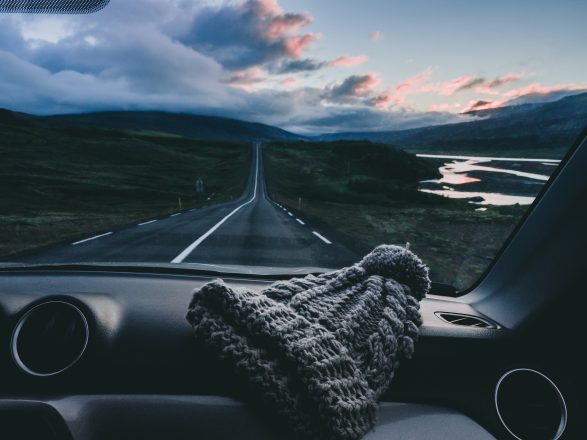 Vista de una carretera en Islandia desde el interior de un coche con gorro de punto en el salpicadero.