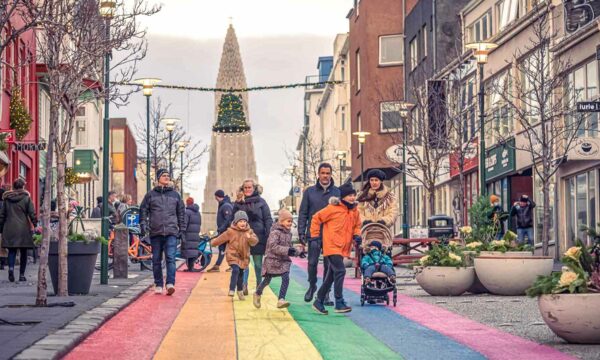 A family walking down a rainbow street under Christmas decorations in Reykjavik, Iceland.