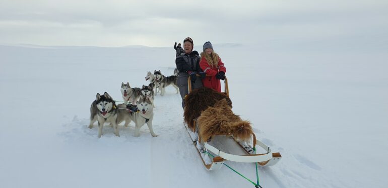 Gente feliz en un trineo tirado por perros en el norte de Islandia