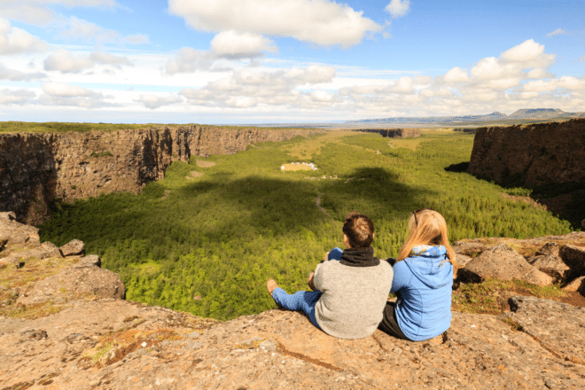 A couple looking over greenery and cliffs at Ásbyrgi Canyon in Iceland.