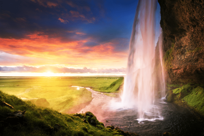 Sunset behind the falling water of Seljalandsfoss Waterfall in South Iceland