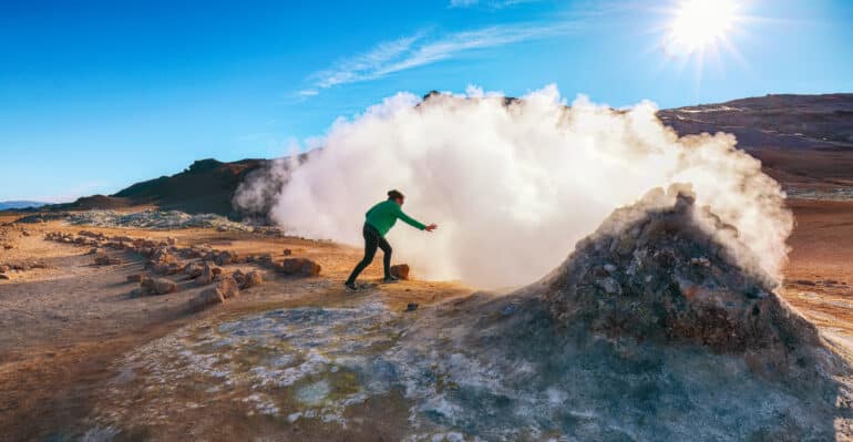Una persona que estira su brazo para sentir el calor de un respiradero de vapor en Námaskarð en la región de Mývatn de Islandia.