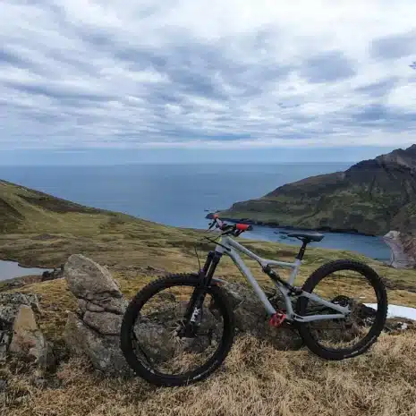 Una sola bicicleta de montaña y un fiordo con un océano azul y verdes colinas al fondo, este de Islandia