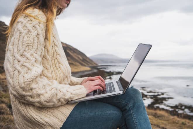Islandia, mujer usando laptop en la costa