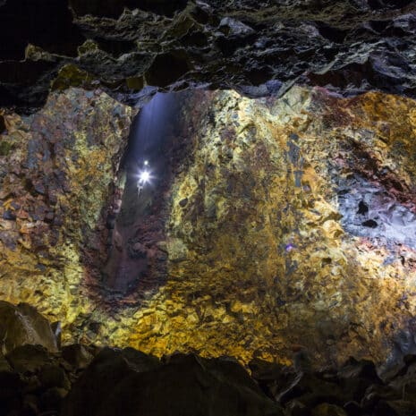 An elevator descending into a vast magma chamber with yellow, blue and purple walls of a dormant volcano in Iceland.