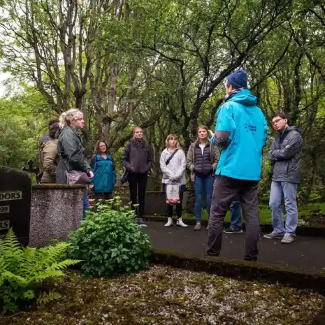 Un guía parado frente a un grupo de personas dentro de un cementerio en Reykjavik, Islandia